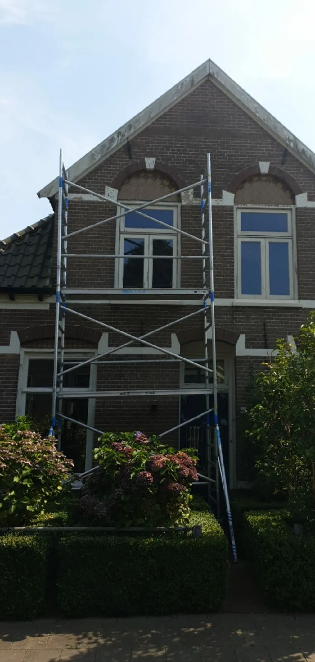 Steiger tegen een woning tijdens buitenschilderwerk