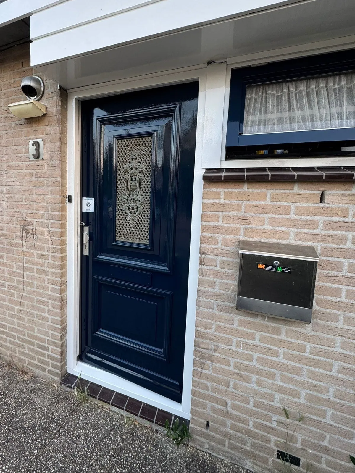 Donkerblauwe voordeur met hoogglans lak in een lichte gevel