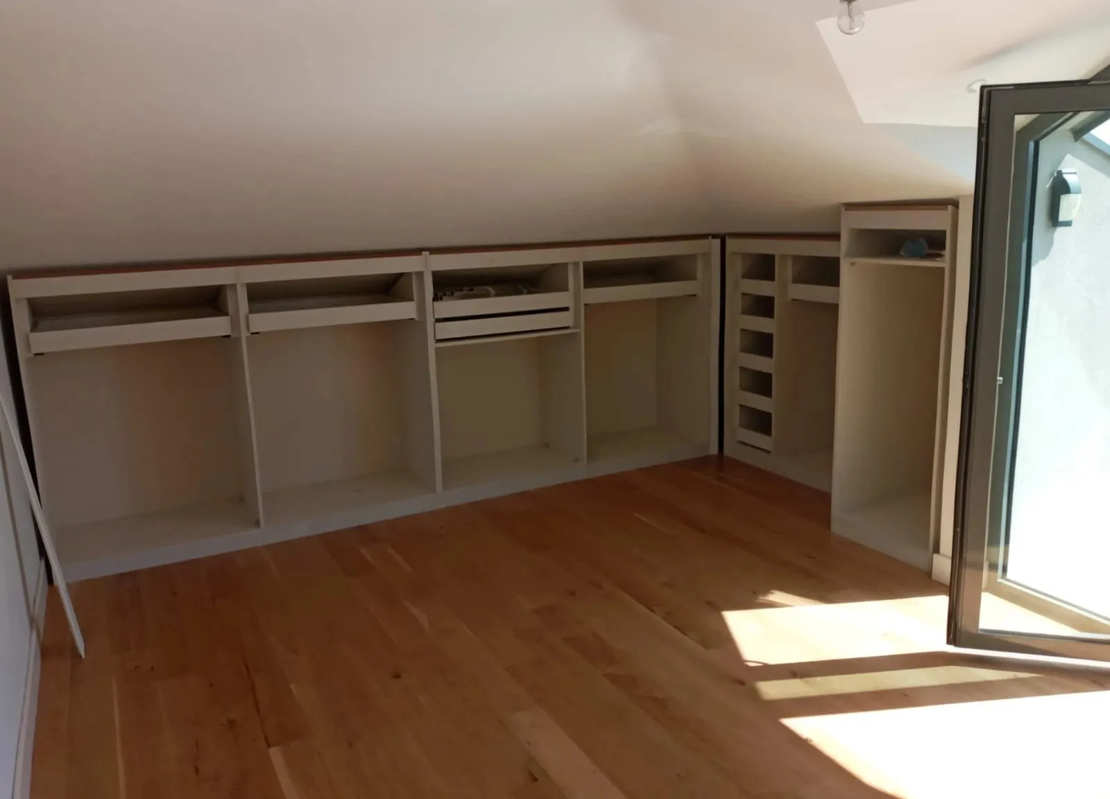 Inbouwkasten met vakken langs de lage wand van een zolder